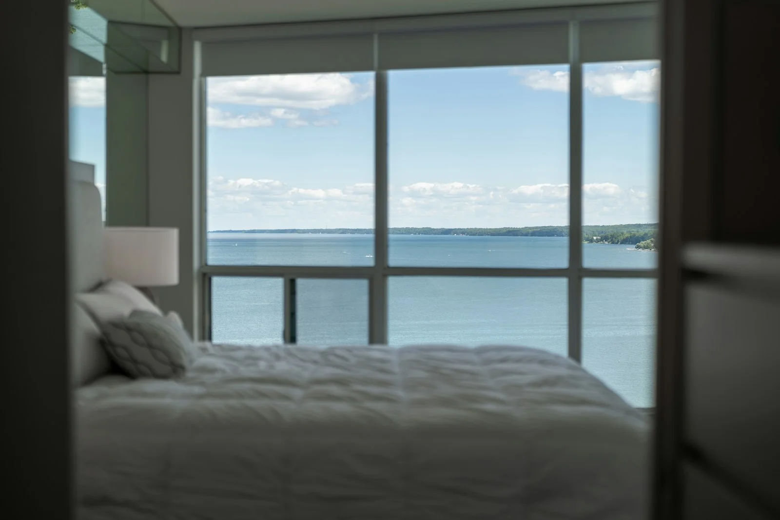A bedroom with a wide window looking straight out to sea