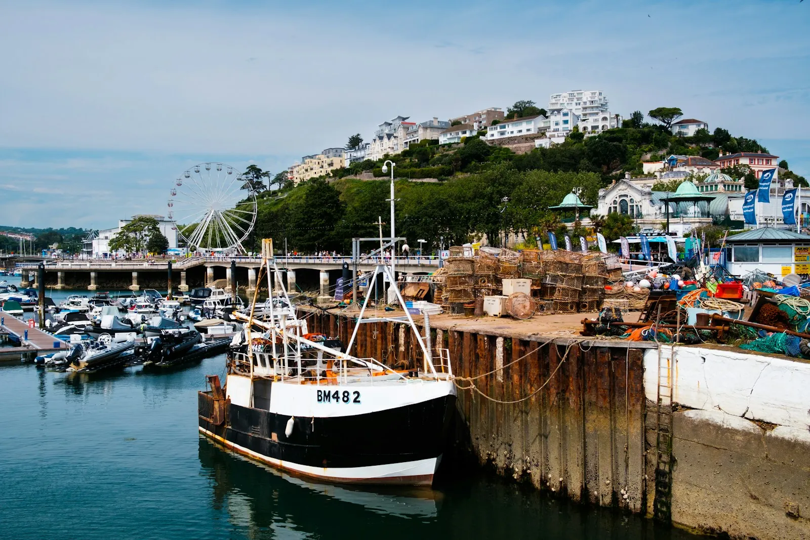 A fishing boat moored at the harbour wall with the town and hillside behind